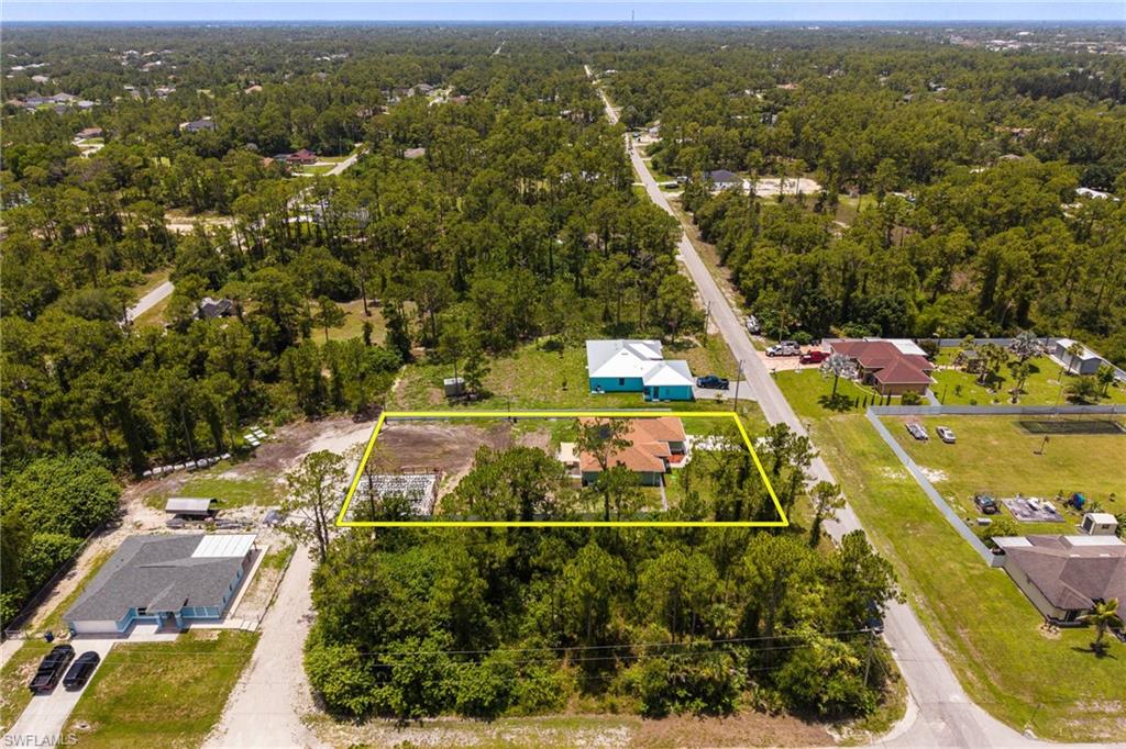 Expansive lot featuring a single-story residence with a red tile roof, surrounded by mature trees