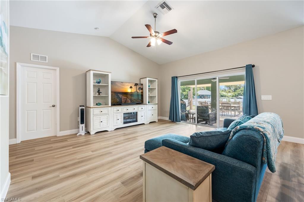 Spacious living area featuring wood-finish flooring, vaulted ceilings, and a ceiling fan