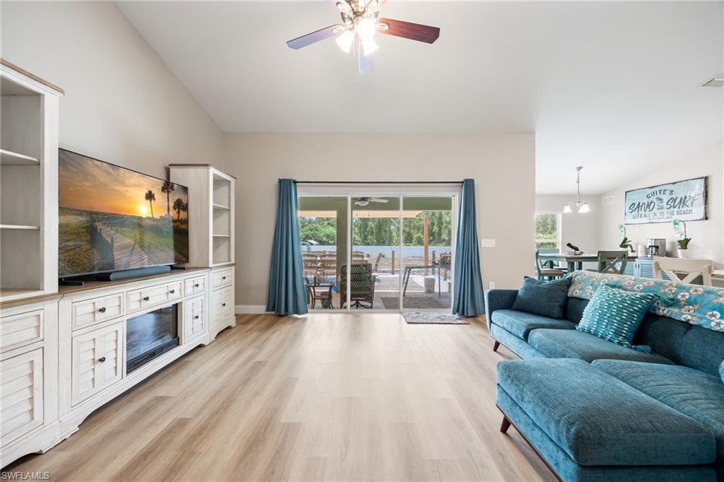 Spacious living area featuring vaulted ceilings, wood-finish flooring, and a ceiling fan