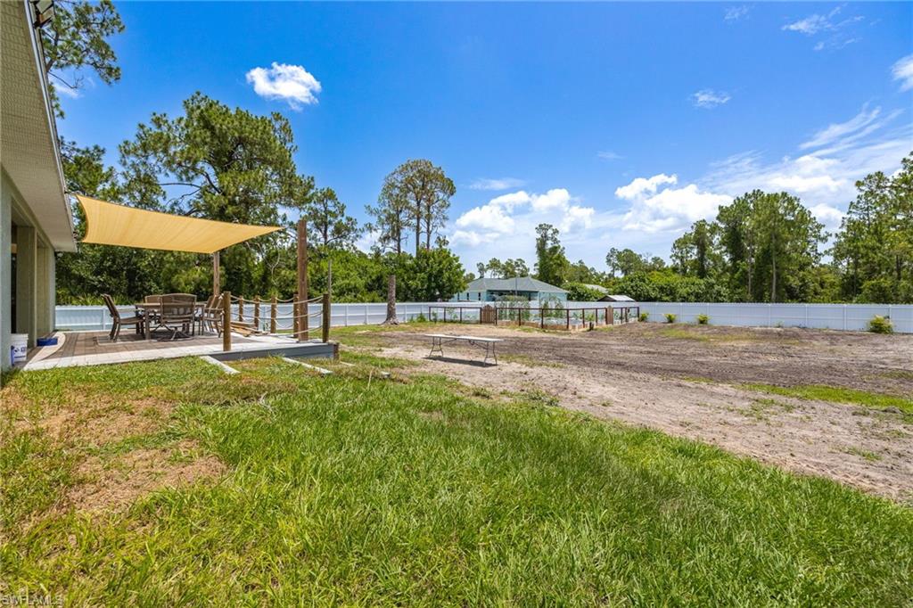 Expansive outdoor space featuring a raised wood-finish deck with a shade sail, a rope and post railing, and a large cleared area