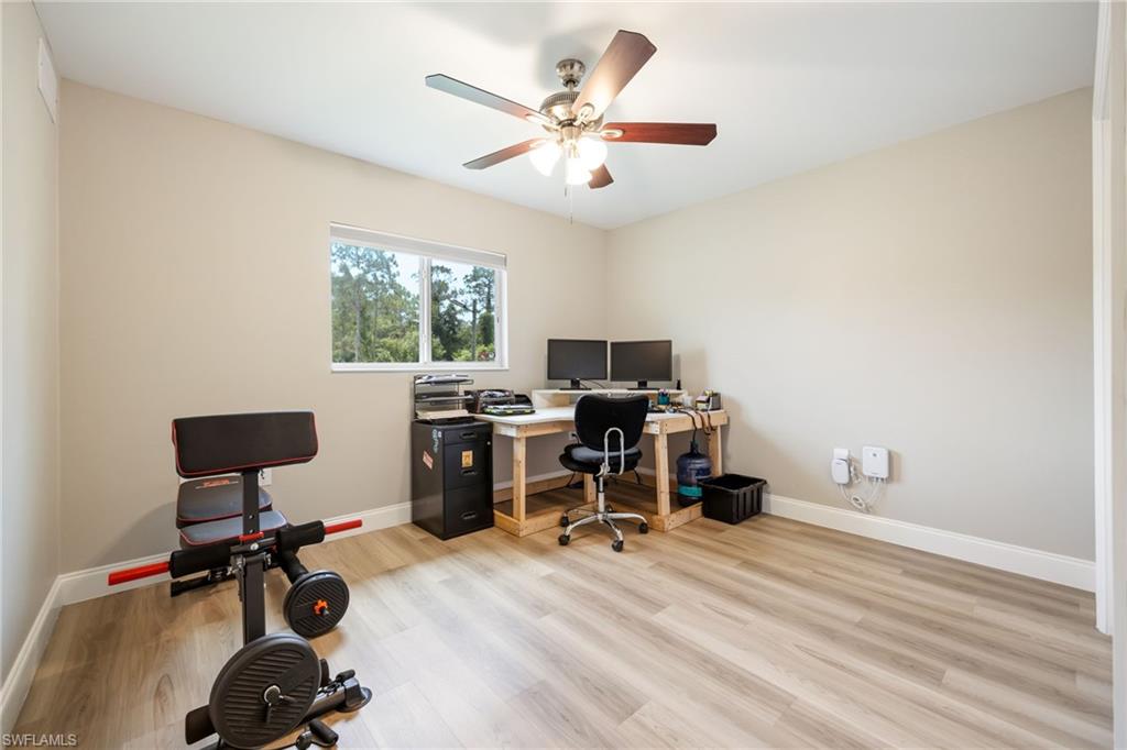 Room featuring wood-finish flooring, neutral wall paint, and a white window frame with a natural backdrop