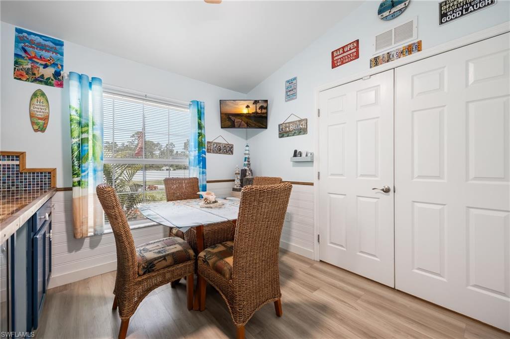 Dining area featuring light wood-finish flooring, a window with horizontal blinds, and a built-in counter with a mosaic tile backsplash