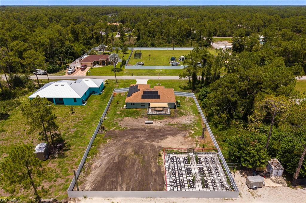 The primary residence features a brown shingle roof with solar panels and an outdoor patio area