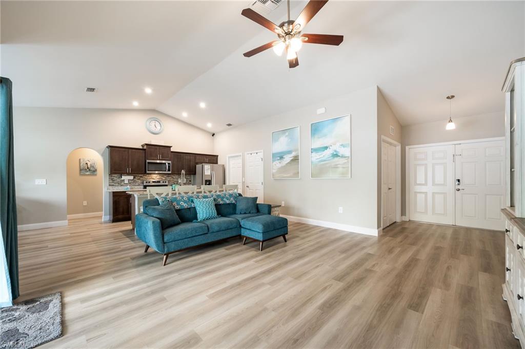 Spacious living area featuring wood-finish flooring, vaulted ceilings, and recessed lighting