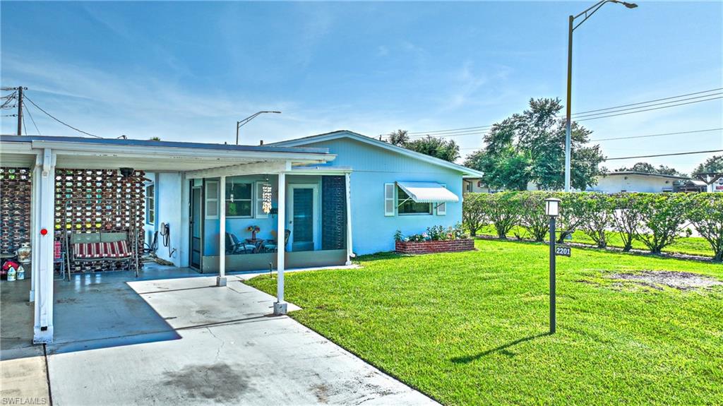 Single-story residence featuring a carport, screened porch, light blue exterior siding, and an awning over a front window