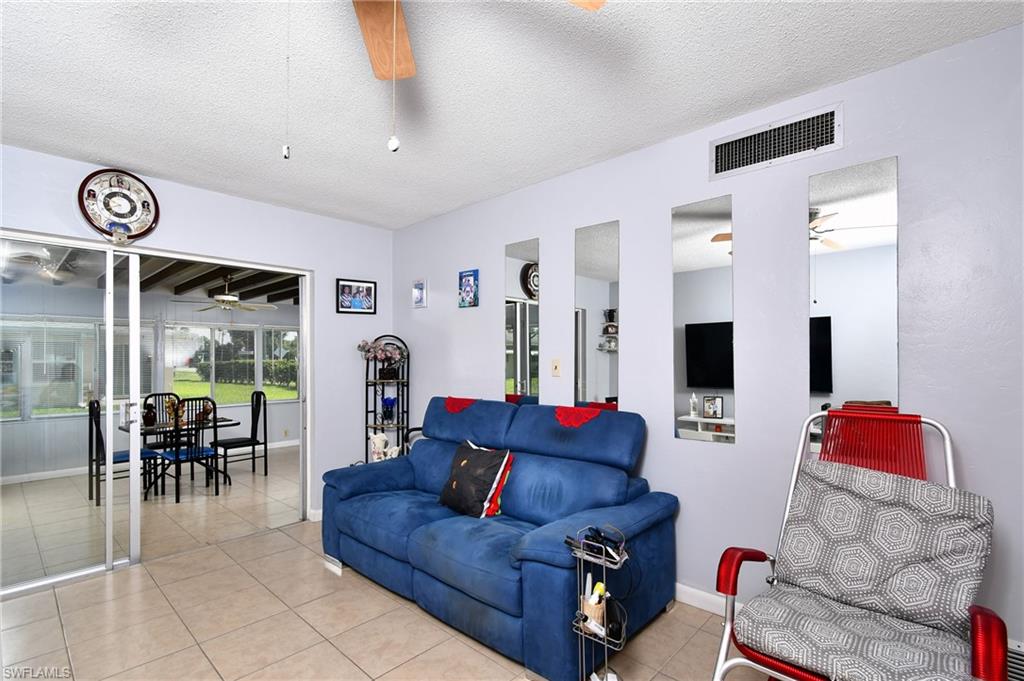 Living area featuring tile flooring, light-toned wall paint, and a ceiling fan with integrated lighting