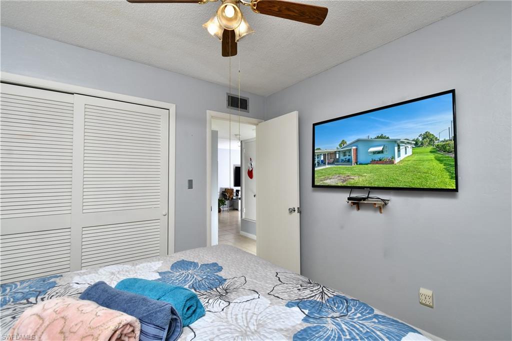 Room featuring a ceiling fan with integrated lighting, louvered bi-fold closet doors, and wall-mounted television