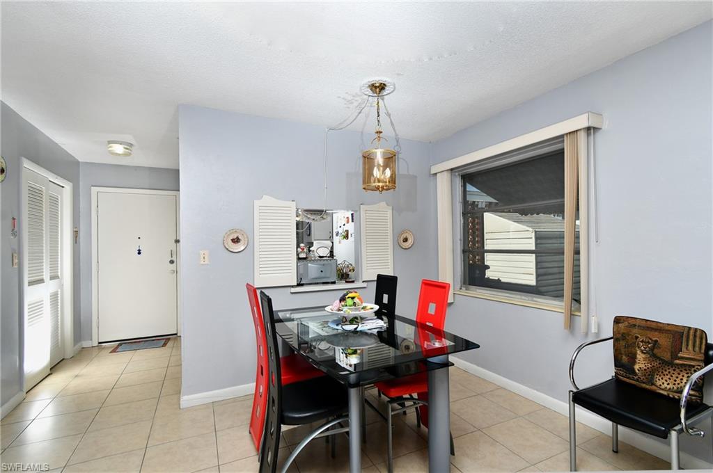 Dining area featuring a contemporary ceiling fixture, a pass-through window with louvered shutters, and a large window with blinds