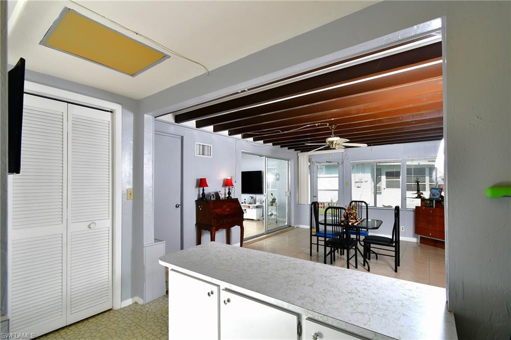 Florida room with counter, white cabinetry, louvered bi-fold doors, and a vaulted beamed ceiling in the adjacent area