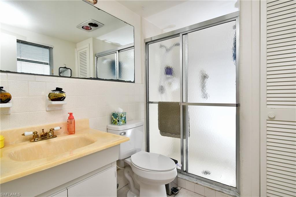 Bathroom featuring a vanity with an integrated sink and brass-finish faucet, a toilet, and a shower enclosure with frosted glass sliding doors