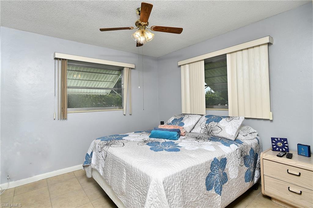 Bedroom featuring dual windows with vertical blinds, a ceiling fan with integrated lighting, and tile flooring