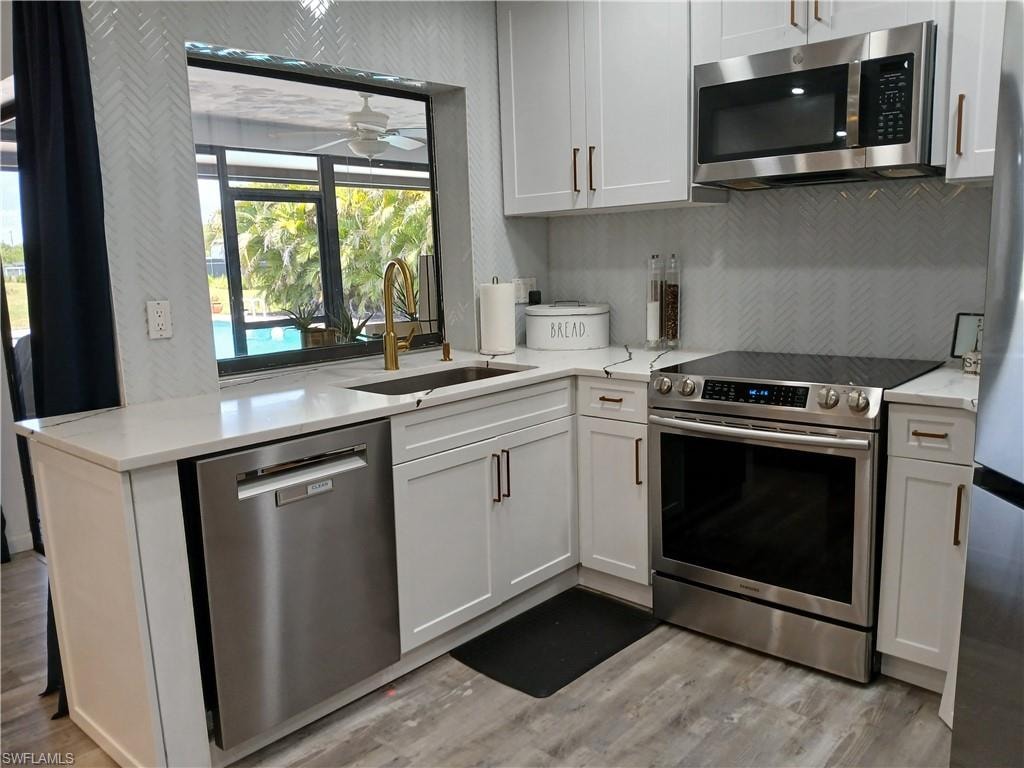 Contemporary kitchen featuring white cabinetry, stainless steel appliances, and a herringbone tile backsplash