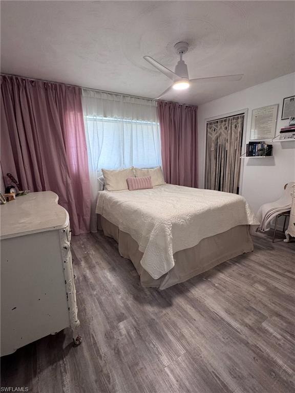 Bedroom featuring wood-finish flooring, a ceiling fan with integrated lighting, and a closet with a decorative macrame covering