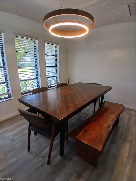 Dining area featuring a contemporary circular chandelier, wood-finish flooring, and multiple windows with blinds
