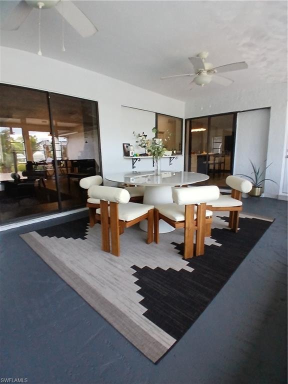 Covered outdoor patio featuring a smooth concrete floor, white ceiling fans, and large sliding glass doors