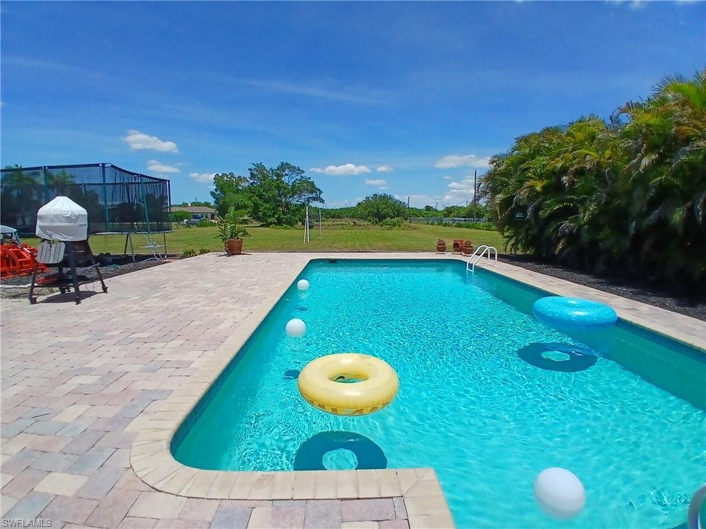 Rectangular inground pool featuring integrated steps and a paver patio surround