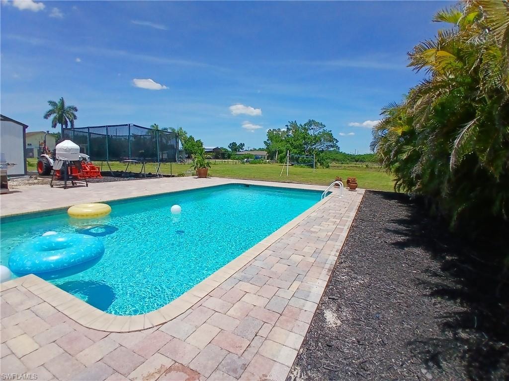 Rectangular swimming pool with paver decking and surrounding landscaped areas