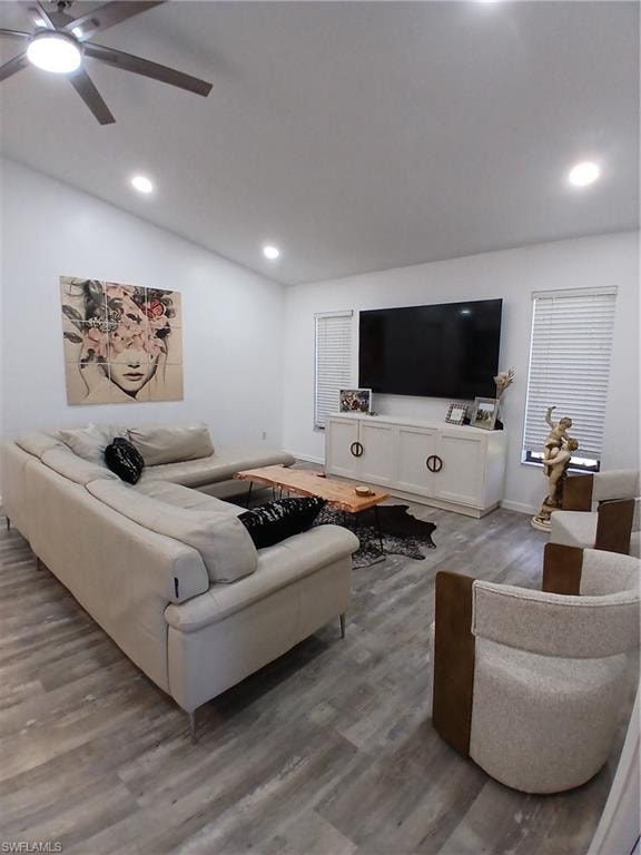 Spacious living area featuring wood-finish flooring, recessed lighting, and a sloped ceiling with a ceiling fan