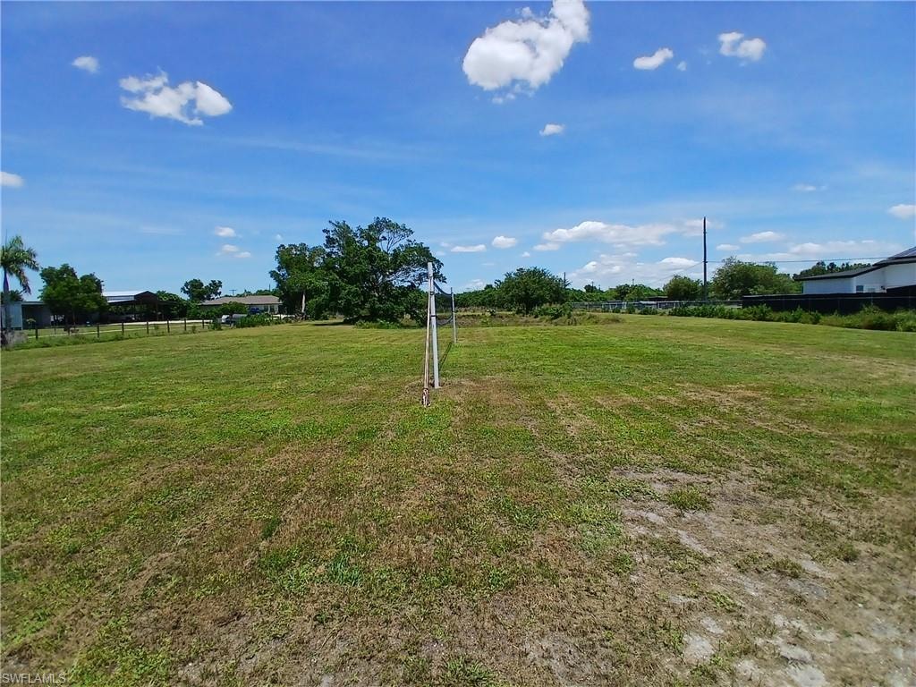 Expansive green space featuring a large grassy area, mature trees, and a clear sky backdrop