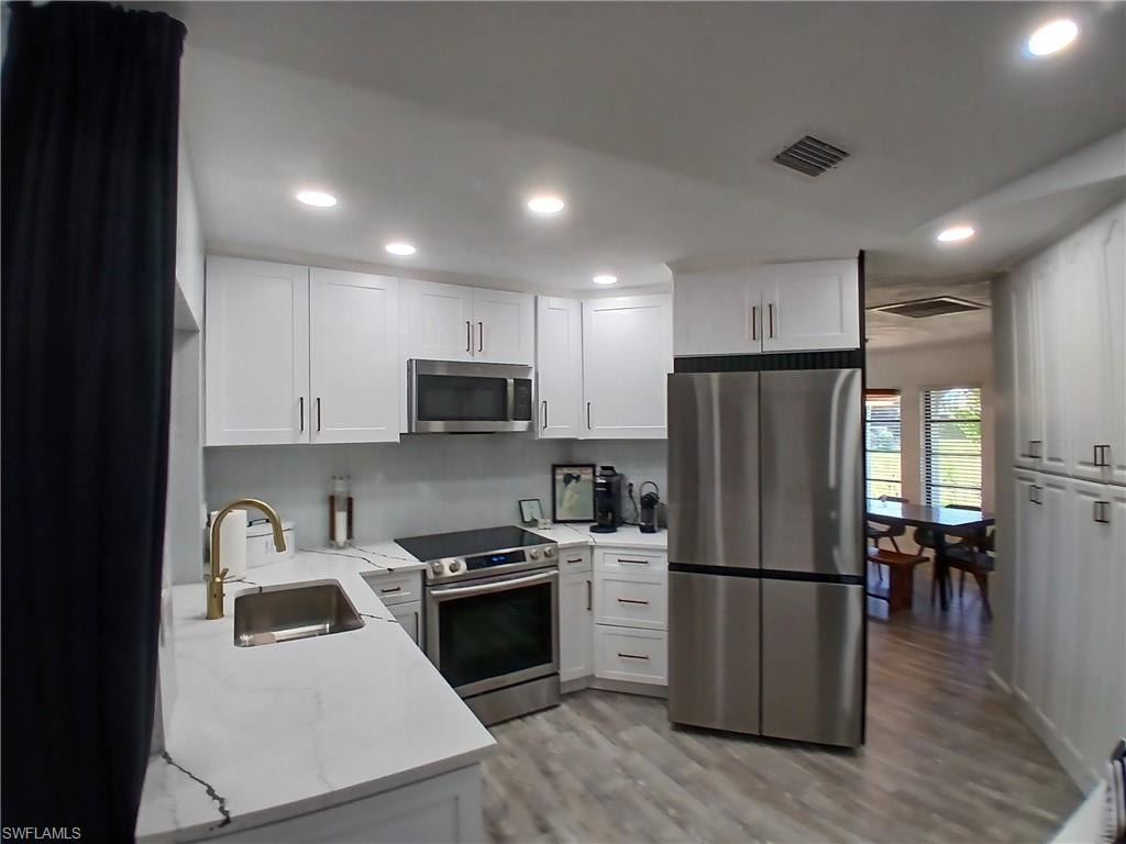 Modern kitchen with white shaker cabinetry, stainless steel appliances, and sleek countertops