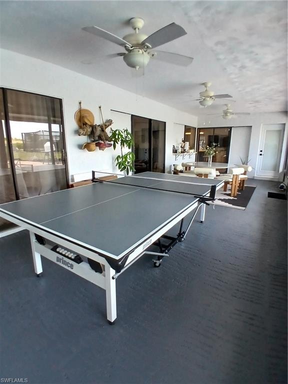 Expansive covered patio featuring multiple ceiling fans, dark gray flooring, and sliding glass doors