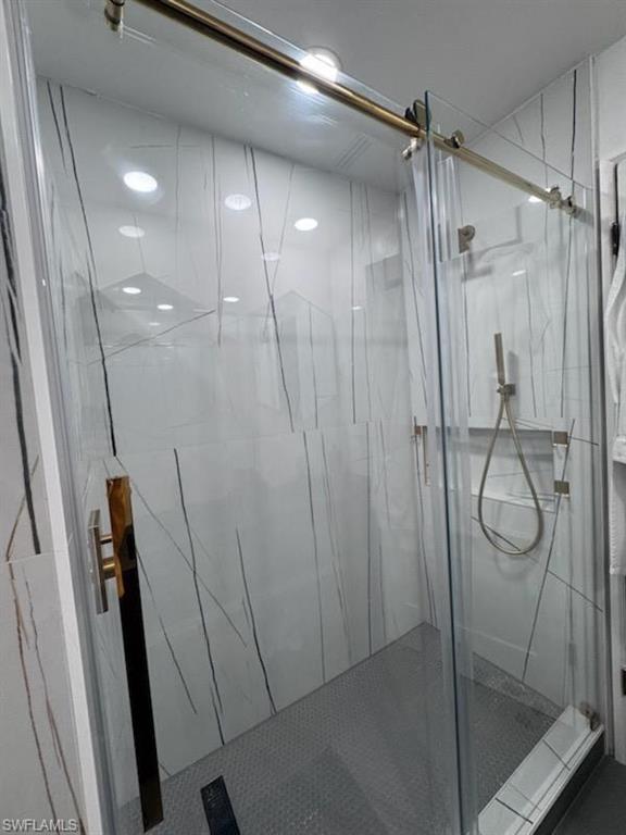 Clear glass shower enclosure with a gold-tone sliding door system, featuring a gold-tone handle