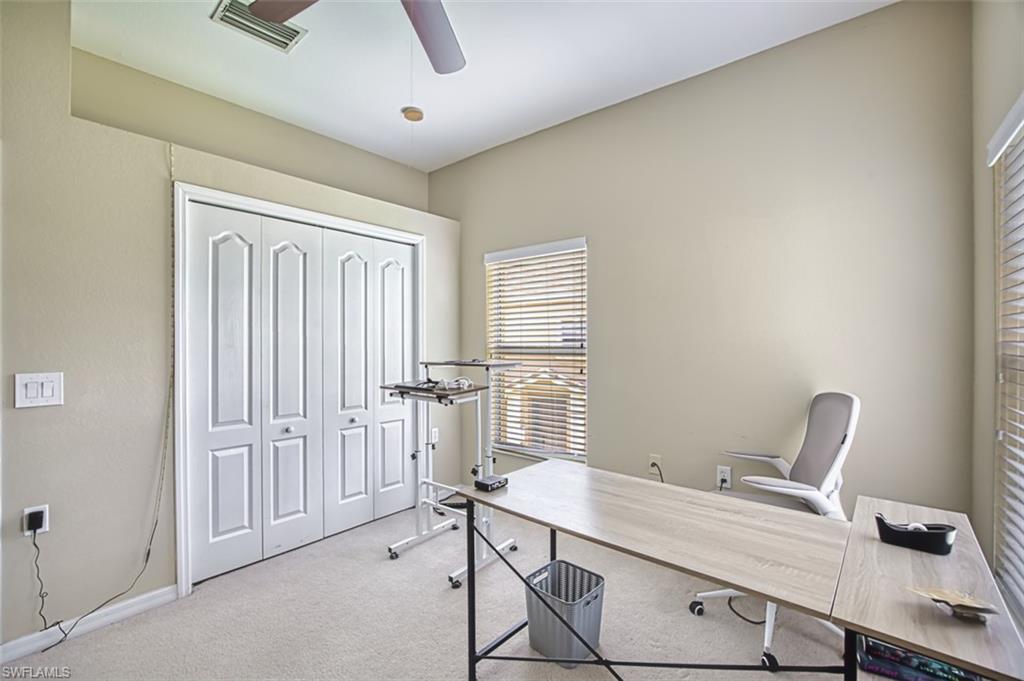 Vaulted ceiling room featuring a ceiling fan with light fixture, carpet flooring, bi-fold closet doors, and window with horizontal blinds