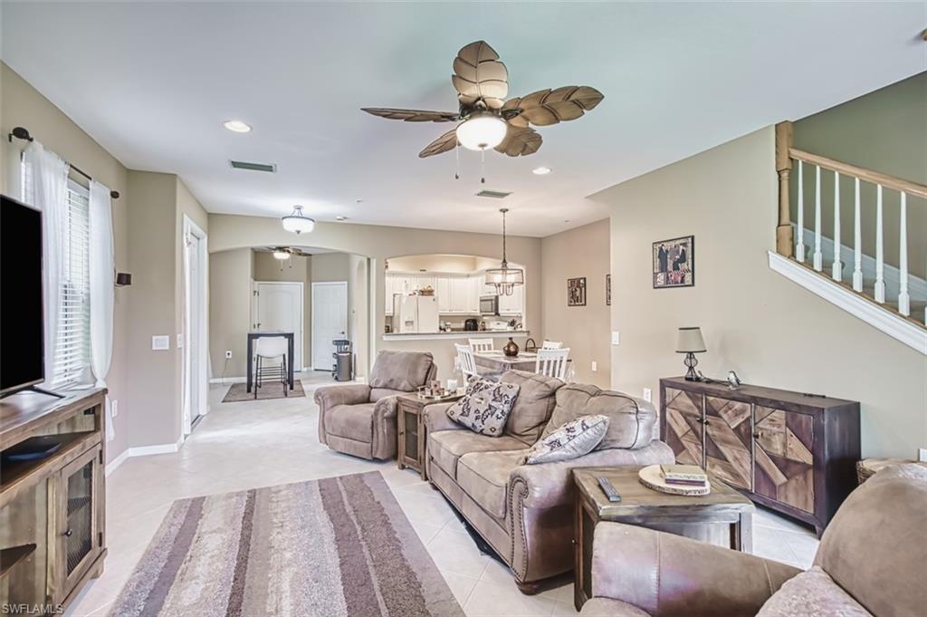 Open-concept living space featuring light-toned tile flooring, recessed lighting, and a ceiling fan with leaf-shaped blades
