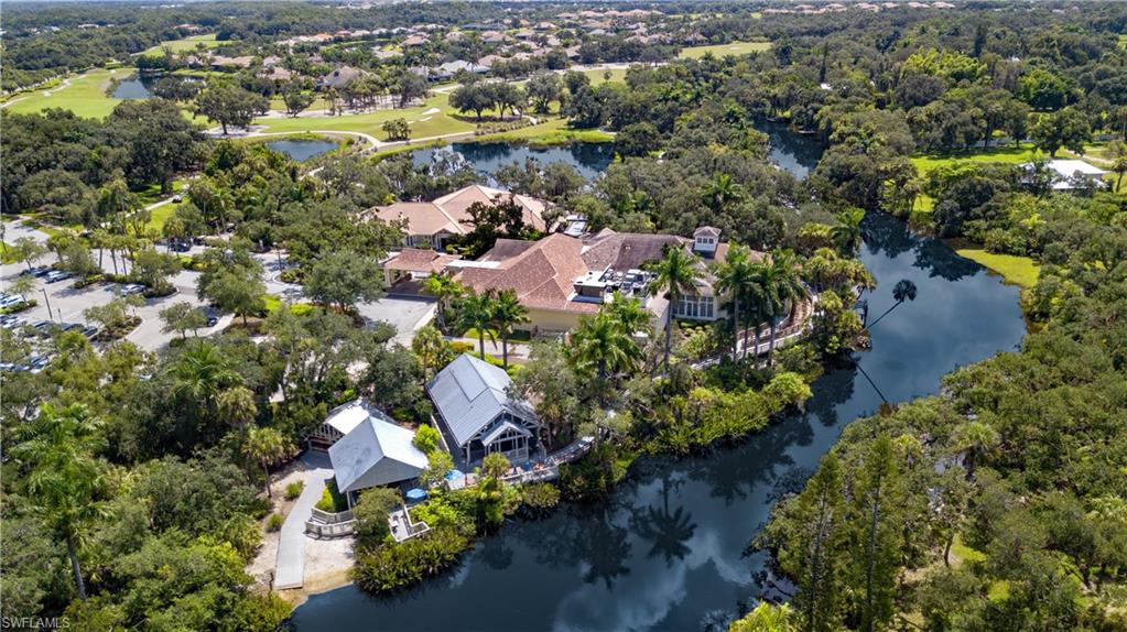 Aerial perspective showcasing a sprawling property featuring multiple structures, a winding waterway, a golf course, and extensive mature landscaping