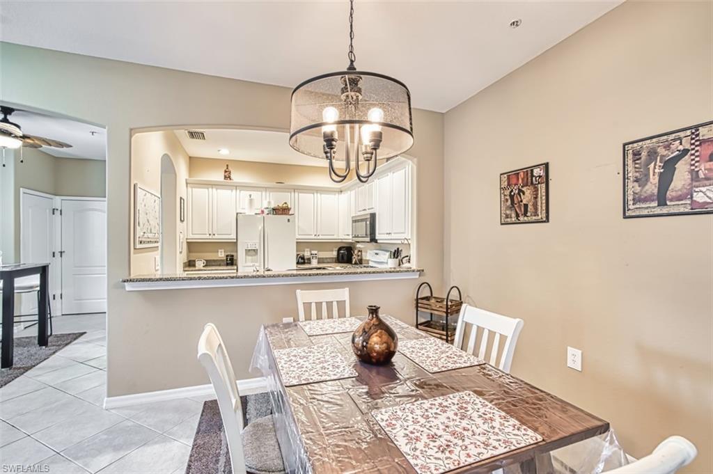 Dining area with an open pass-through to the kitchen featuring white cabinetry, a built-in microwave, and a white refrigerator