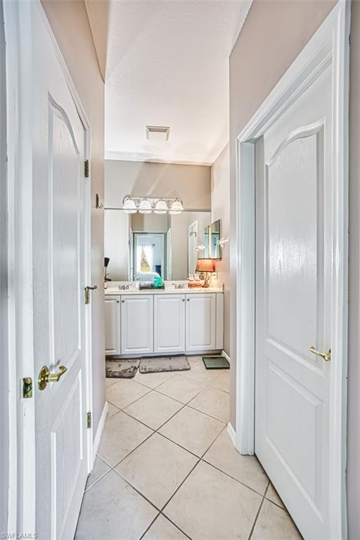 Bathroom vanity featuring dual sinks, white cabinetry, and a multi-bulb vanity light fixture