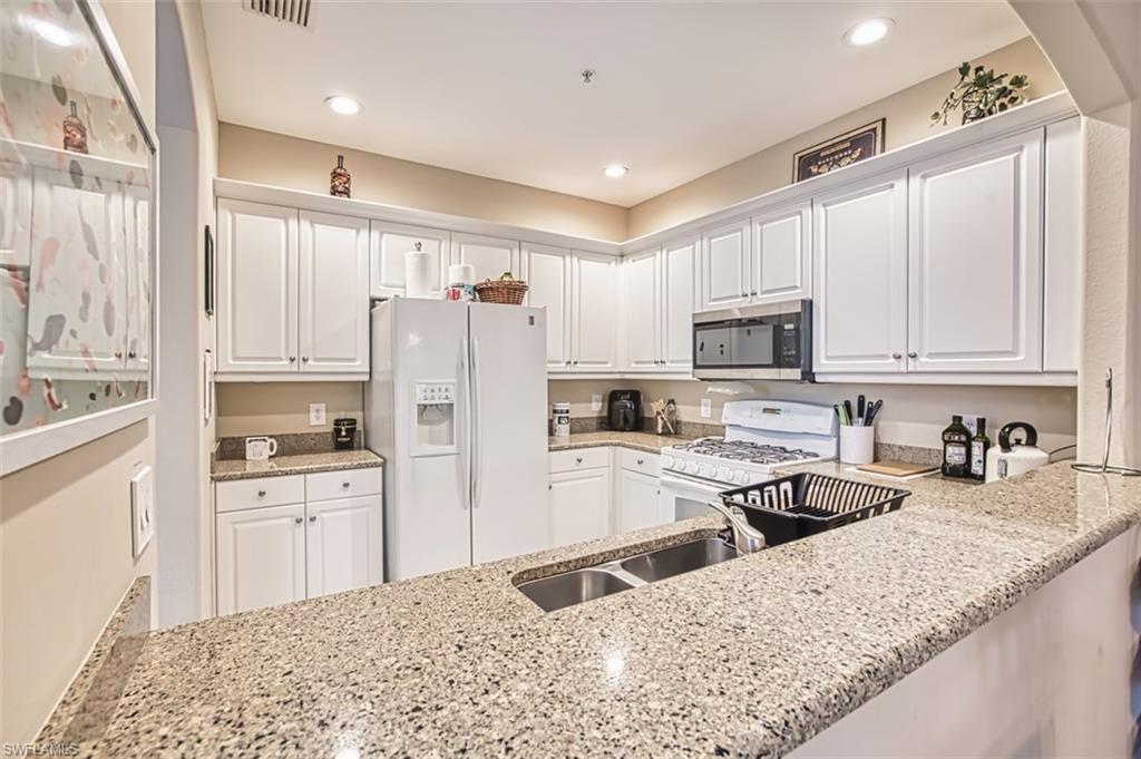 Kitchen featuring white cabinetry, granite countertops, a double basin stainless steel sink, and recessed lighting