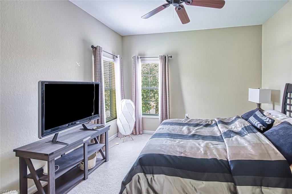 Carpeted room featuring a ceiling fan, two windows with blinds and drapes, and neutral wall tones