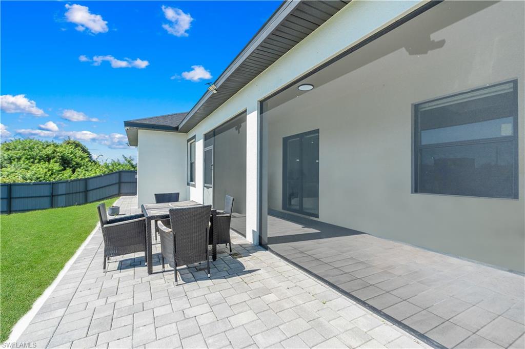 Spacious paver patio with a screened lanai area, offering a direct walkout to a manicured lawn