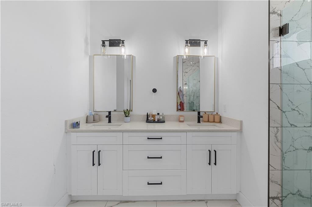 Dual vanity with white cabinetry, light-toned countertops, and matte black hardware