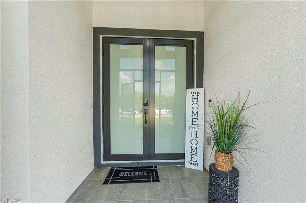 Contemporary double entry doors with dark frames and glass panels, set within a stucco facade