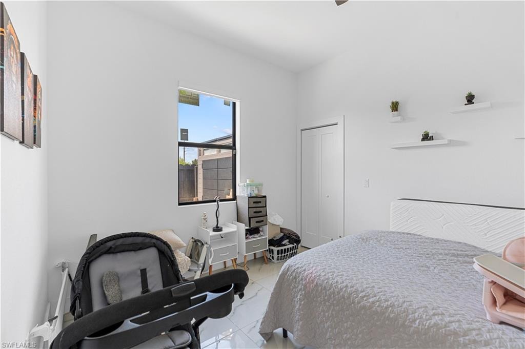 Bedroom featuring white walls, bright window, tile flooring, and closet with bifold doors