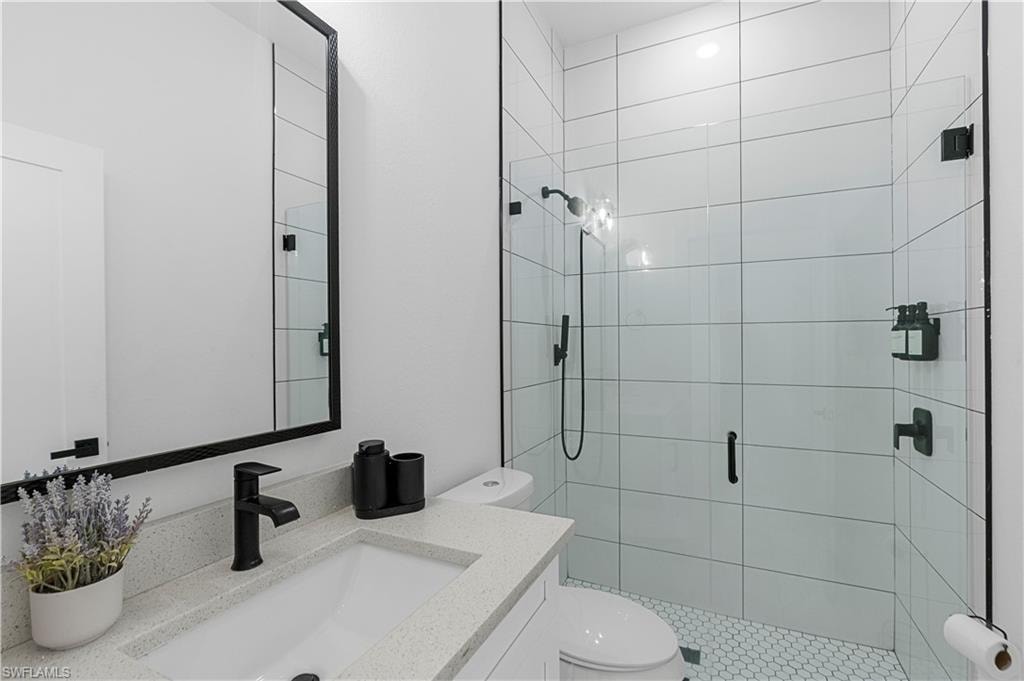 Bathroom featuring a walk-in shower with clear glass enclosure, white rectangular tile walls, and hexagonal floor tile