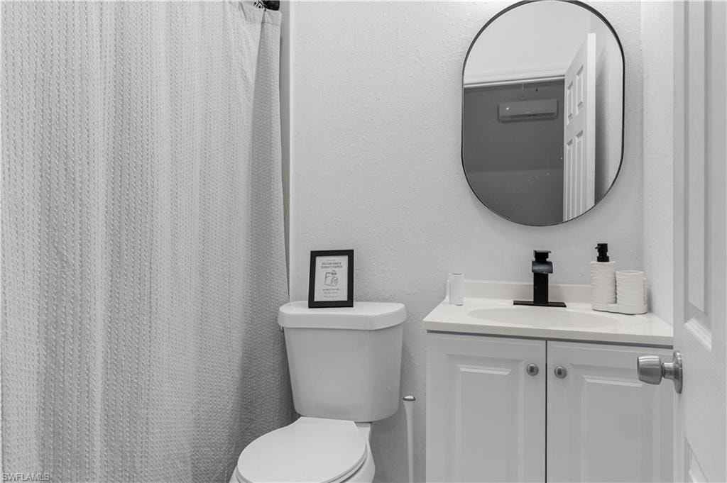 Bathroom featuring a white vanity with a light-toned countertop, a black faucet, and an oval-shaped mirror