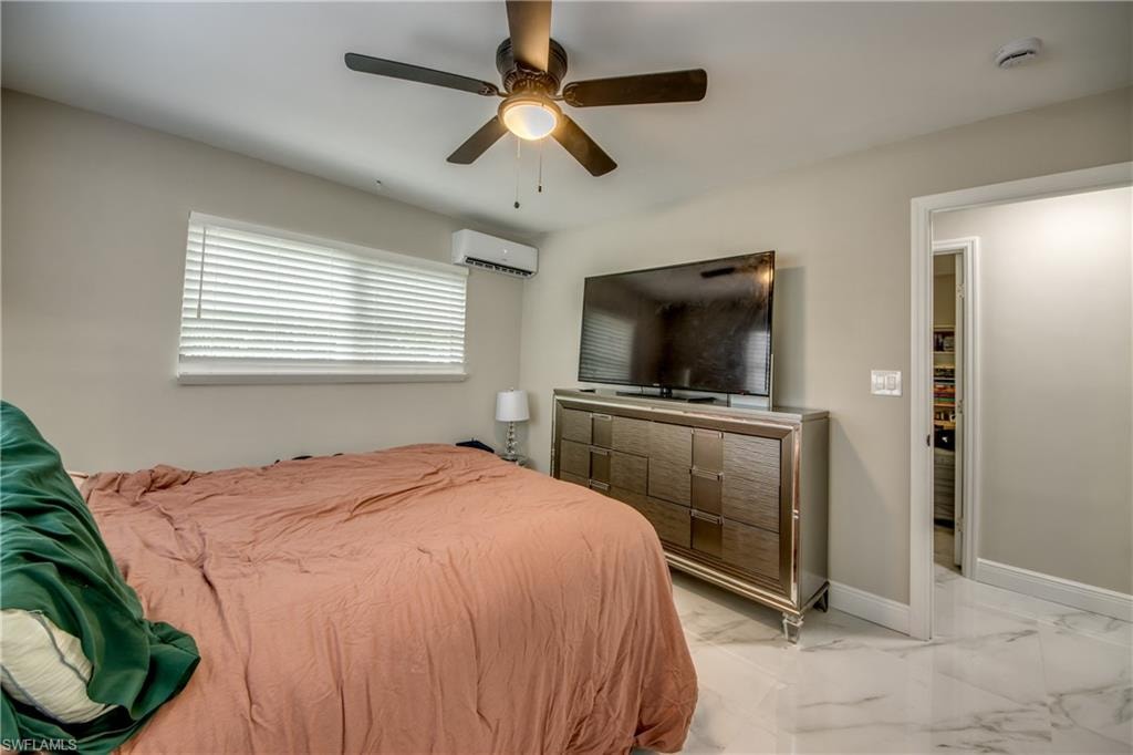 Bedroom featuring a ceiling fan with integrated lighting, a window with horizontal blinds, a wall-mounted mini-split air conditioning unit, and white tile flooring