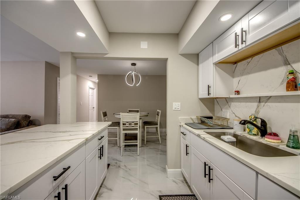 Kitchen featuring white cabinetry, stone-look countertops, and a coordinating backsplash