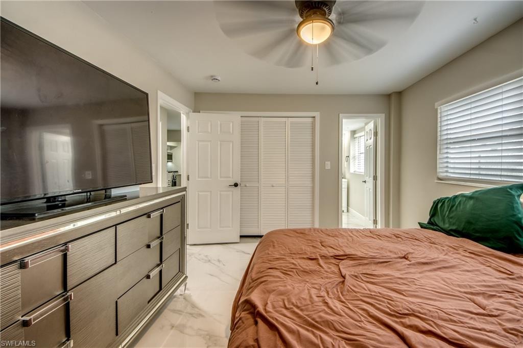 Bedroom featuring white tile flooring, ceiling fan with integrated lighting, and louvered closet doors
