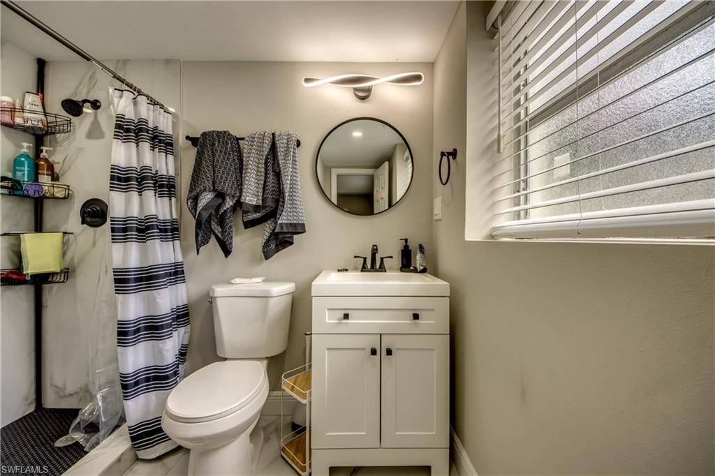 Contemporary bathroom featuring a white vanity with black hardware, a round mirror, and an overhead light fixture