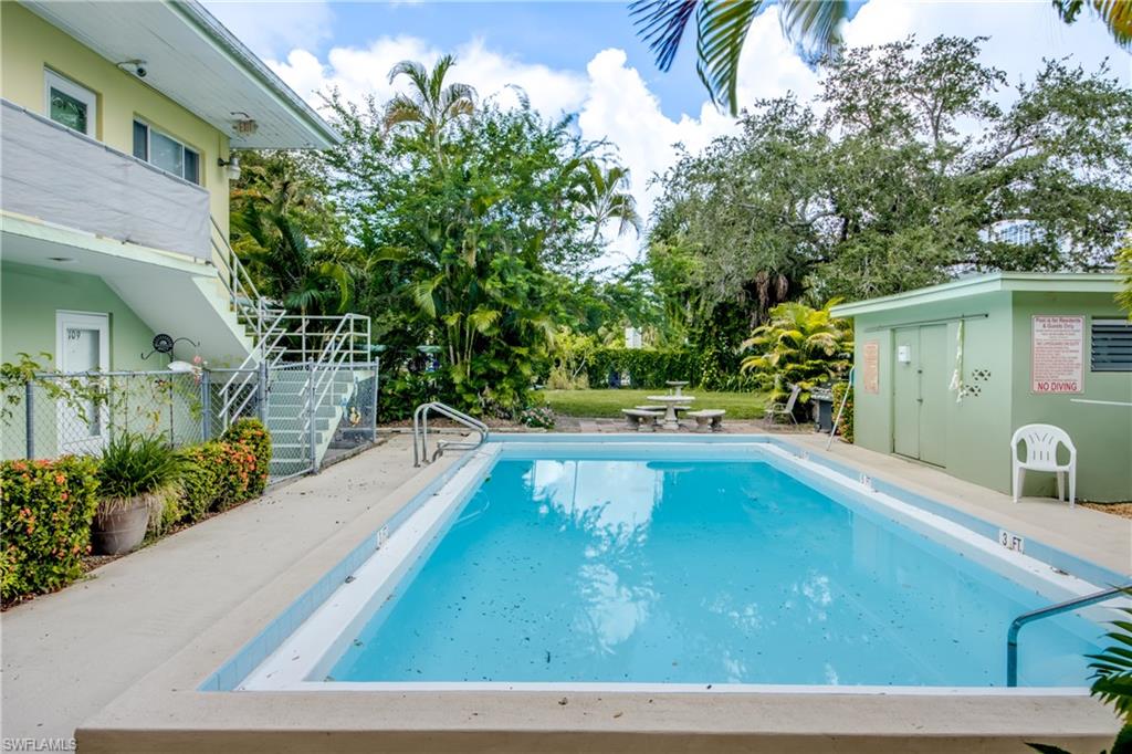 Rectangular swimming pool with concrete decking, surrounded by mature trees and lush landscaping