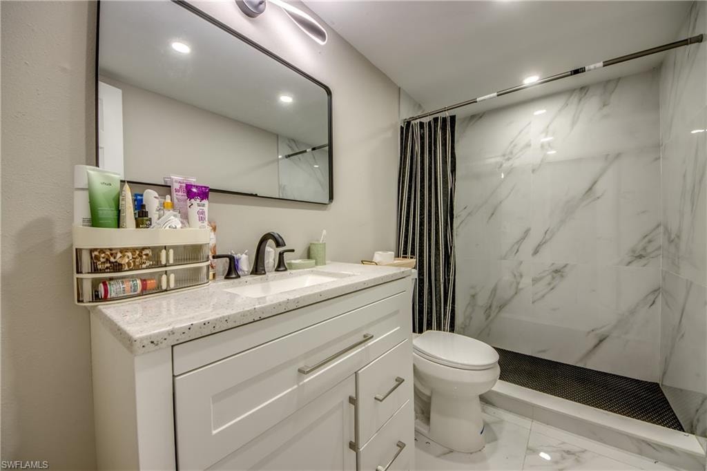 Bathroom featuring a white vanity with an integrated sink, black faucet, and speckled countertop