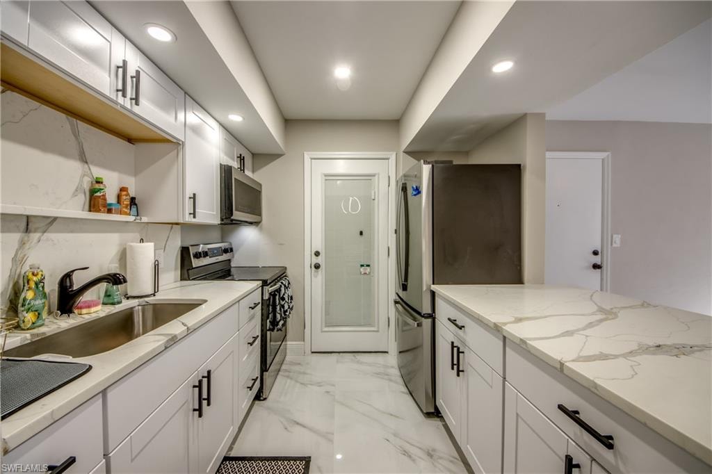 Contemporary kitchen featuring white cabinetry with matte black hardware, stainless steel appliances, and sleek countertops