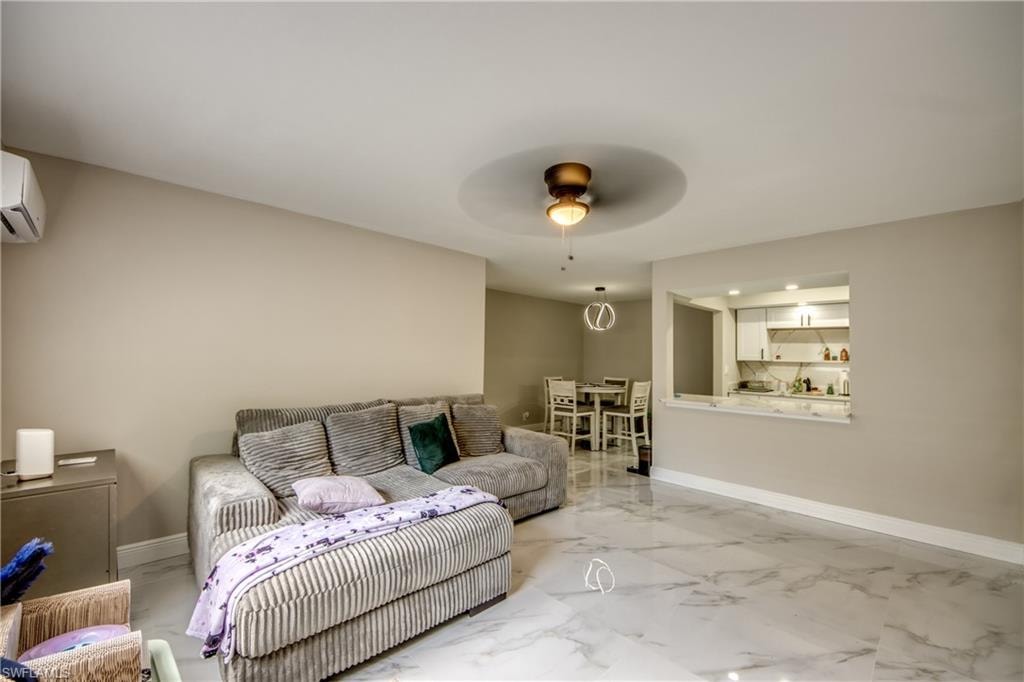 Open-concept living area featuring light-toned walls, large format marble-look flooring, and a recessed ceiling fan with integrated lighting