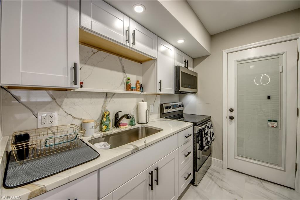 Modern kitchen featuring white shaker cabinetry, stone-finish countertops, and a full-height backsplash with a striking vein pattern