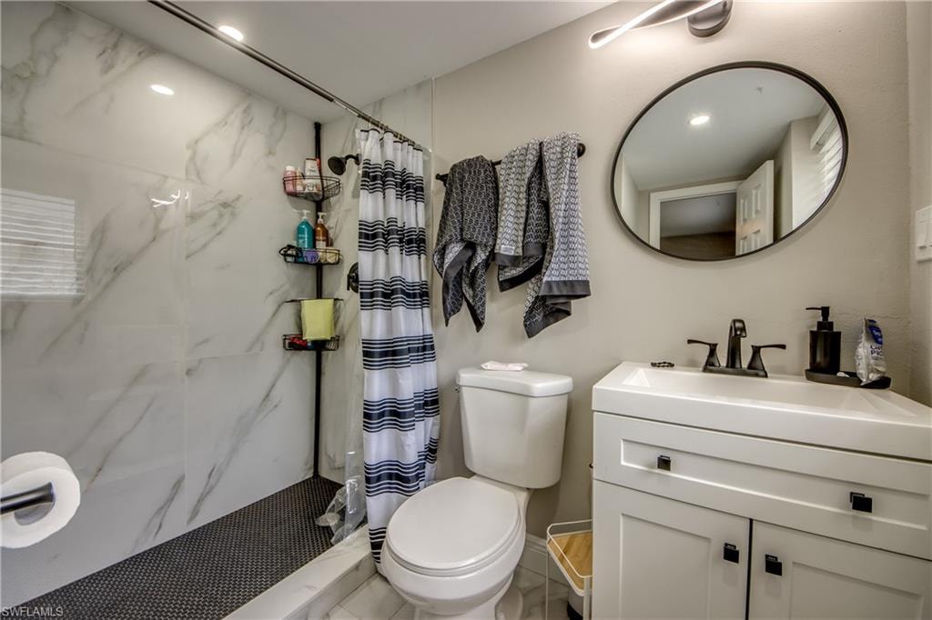 Shower featuring large format marble-look wall tiling and dark penny tile flooring