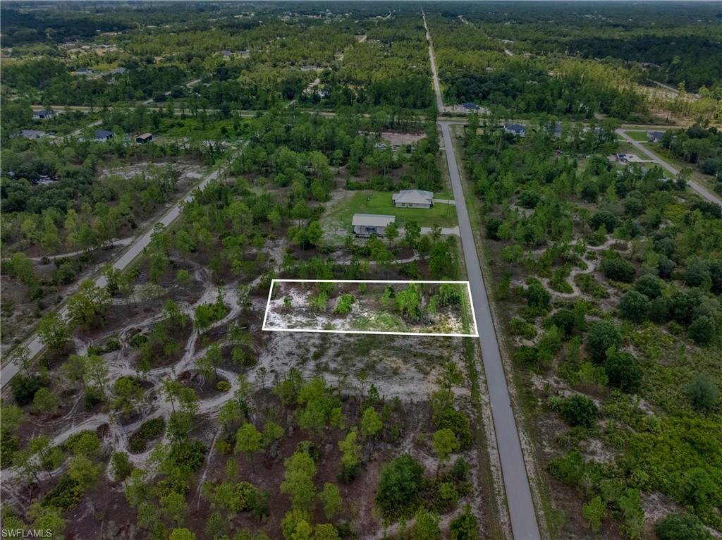 Aerial perspective showcasing a vacant parcel with a white outline, bordered by a paved road